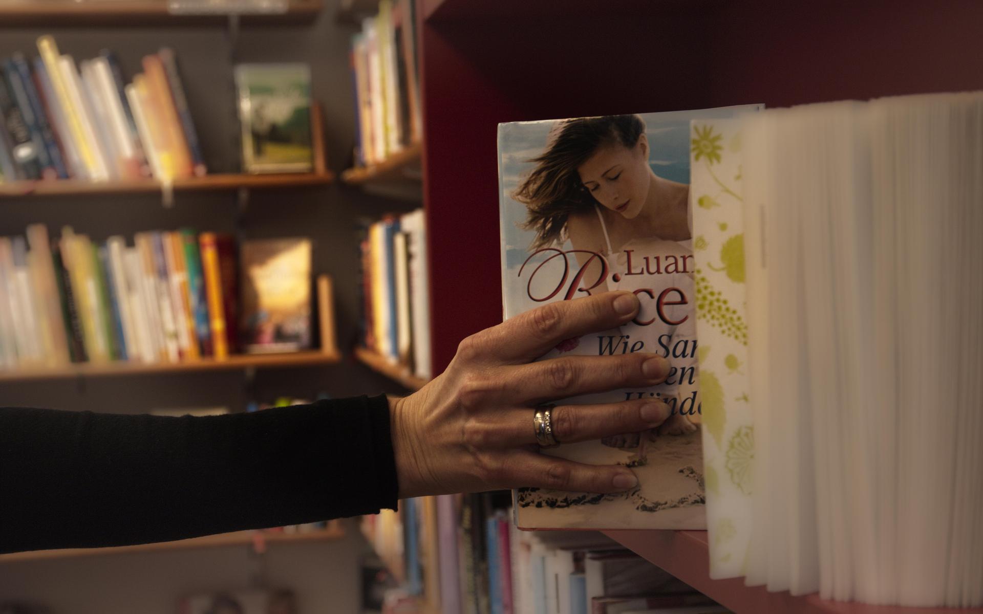 Bibliothek Oberlienz Leser nimmt Buch aus Regal